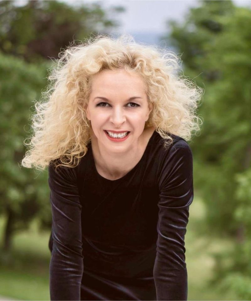 Porträt von Yasmin Schwarze mit blonden Locken, lächelnd, im Grünen